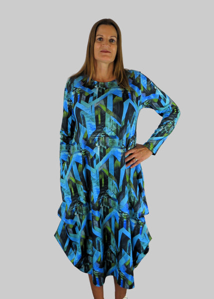 This hitch up dress is made from a soft feel jersey fabric, with an all over shades of blue print. The dress has a hitch up hem on both sides, which can be buttoned up or let down for a longer length. Perfect for any autumn / winter occasion from a wedding, mother of the bride, mother of the groom to a party or everyday wear. This dress will take you from day to night with effortless style and elegance. Available in Abstract Aqua, Fuchsia, Green , Fusion print and Aqua.