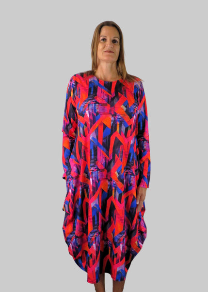 This hitch up dress is made from a soft feel jersey fabric, with an all over shades of pink and red print. The dress has a hitch up hem on both sides, which can be buttoned up or let down for a longer length. Perfect for any autumn / winter occasion from a wedding, mother of the bride, mother of the groom to a party or everyday wear. This dress will take you from day to night with effortless style and elegance. Available in Abstract Aqua, Fuchsia, Green & Fusion print and Aqua.