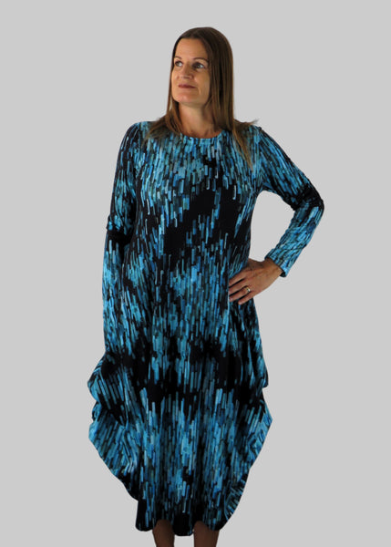 This hitch up dress is made from a soft feel jersey fabric, with an all over shades of blue print. The dress has a hitch up hem on both sides, which can be buttoned up or let down for a longer length. Perfect for any autumn / winter occasion from a wedding, mother of the bride, mother of the groom to a party or everyday wear. This dress will take you from day to night with effortless style and elegance. Available in Abstract Aqua, Fuchsia, Green & Fusion print and Aqua.